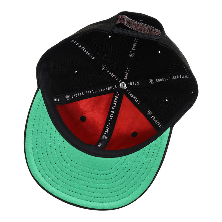 A black Indianapolis Indians MiLB Snapback Ballcap by Ebbets Field, shown from underneath, features a green brim, red interior, black sweatband, and inner seam labels reading EBBETS FIELD FLANNELS and GARRETT.
