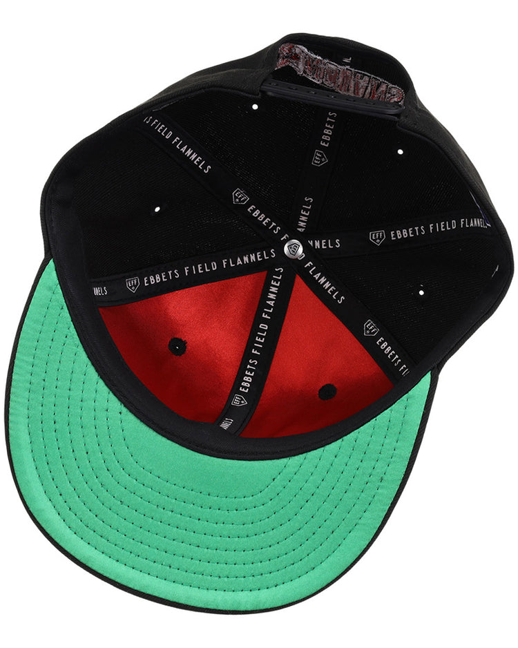 A black Indianapolis Indians MiLB Snapback Ballcap by Ebbets Field, shown from underneath, features a green brim, red interior, black sweatband, and inner seam labels reading EBBETS FIELD FLANNELS and GARRETT.