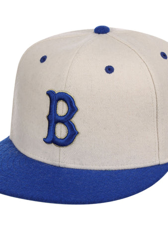 The Ebbets Field Brooklyn Royal Giants NLB Ballpark Fitted Ballcap features a beige crown with blue brim, top button, embroidered B on the front, and blue eyelets.