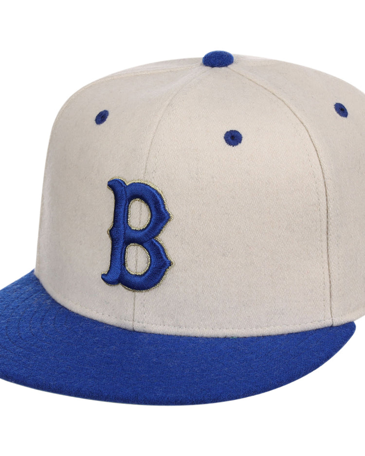The Ebbets Field Brooklyn Royal Giants NLB Ballpark Fitted Ballcap features a beige crown with blue brim, top button, embroidered B on the front, and blue eyelets.