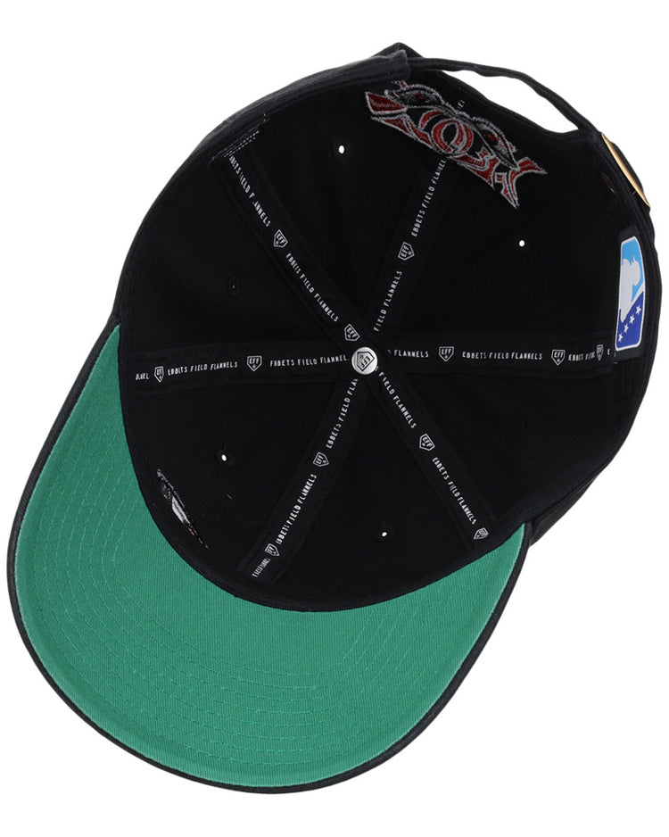 The Lake Elsinore Storm MiLB Dad Ballcap by Ebbets Field is shown from below, displaying its green underbrim, black inner lining with printed text and logos, and several attached tags inside.