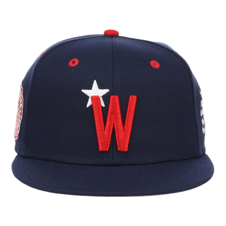 The Ebbets Field Washington Black Senators NLB Varsity Fitted Ballcap is navy with a red brim button, red ventilation holes, and features a large red 