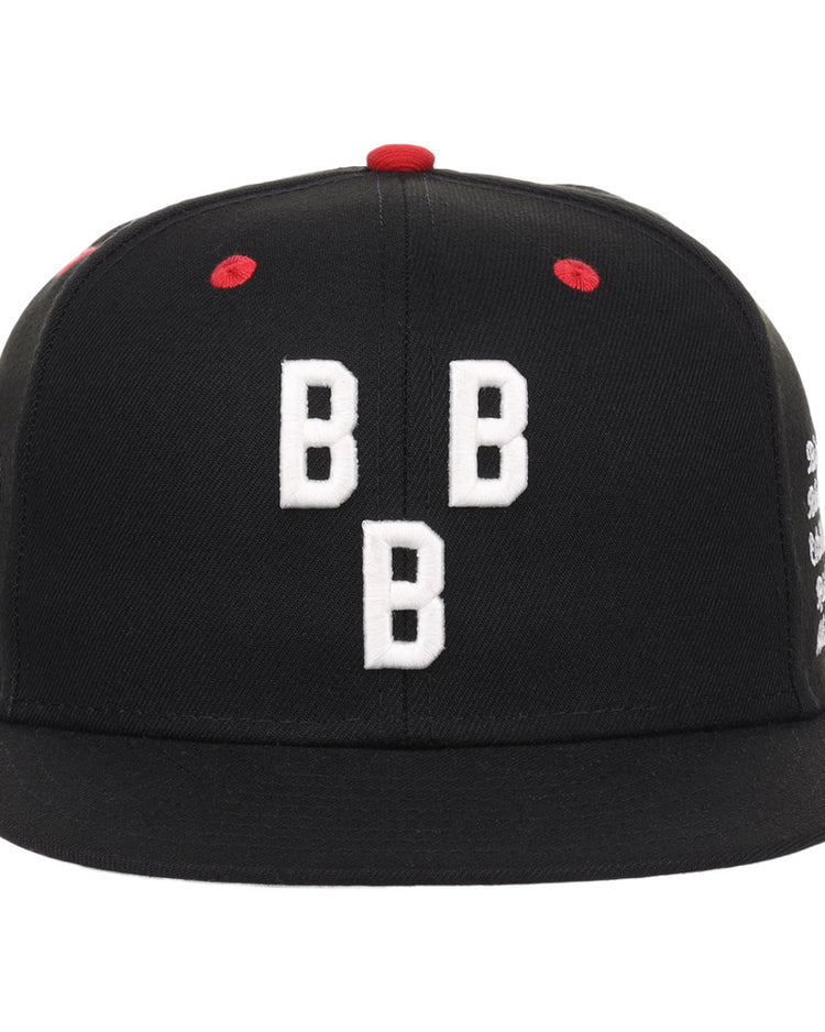 The Birmingham Black Barons NLB Varsity Fitted Ballcap by Ebbets Field is a black hat featuring three white embroidered Bs on the front and red stitching accents.