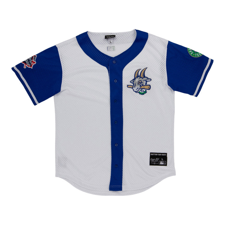The Ebbets Field Hartford Yard Goats MiLB Button Down Jersey is white with blue sleeves and trim, a cartoon goat logo on the chest, sleeve patches, button-down front, and a black label near the hem.