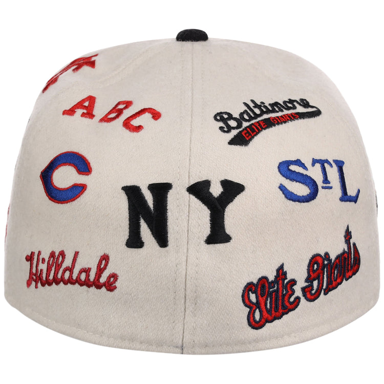 The Ebbets Field Negro League Baseball NLB Ballpark Fitted Ballcap is a white cap embroidered in red, black, and blue with vintage team logos and names like NY, STL, Elite Giants, Hilldale, Baltimore Elite Giants, and ABC.
