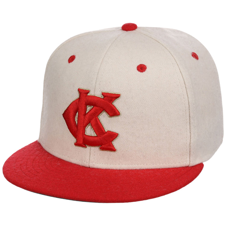 The Kansas City Monarchs NLB Ballpark Fitted Ballcap by Ebbets Field is beige with a red interlocking KC logo on the front, plus red eyelets and a red top button.