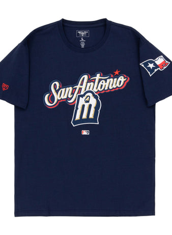 The Ebbets Field San Antonio Missions MiLB Fashion Cotton Short Sleeve Tee features a navy design with San Antonio and an M logo on the front, a Texas flag patch on the right sleeve, and an MLB logo below the graphic.