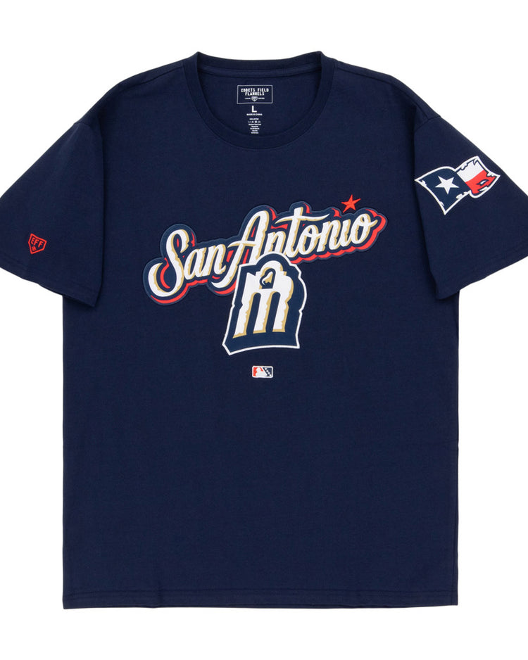 The Ebbets Field San Antonio Missions MiLB Fashion Cotton Short Sleeve Tee features a navy design with San Antonio and an M logo on the front, a Texas flag patch on the right sleeve, and an MLB logo below the graphic.