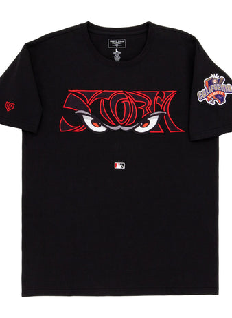 The Ebbets Field Lake Elsinore Storm MiLB Fashion Cotton Short Sleeve Tee is a black shirt with bold red-outlined cartoon eyes on the chest, an MLB logo underneath, and a colorful 