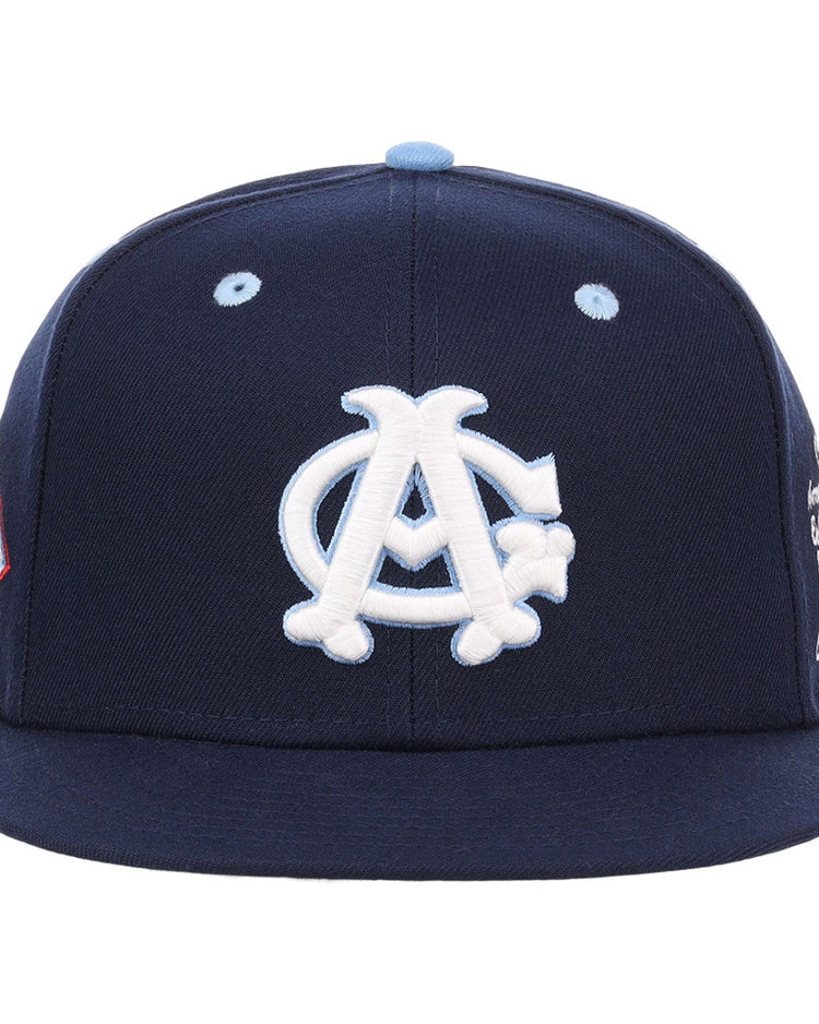 The Ebbets Field Chicago American Giants NLB Varsity Fitted Ballcap features a navy blue body, white interlocking A and C logo, light blue eyelets, flat brim, and additional side panel patches.
