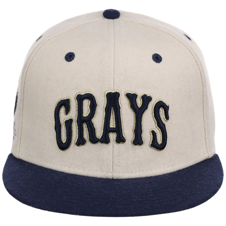 The Ebbets Field Homestead Grays NLB Ballpark Fitted Ballcap has a beige crown, dark blue brim, and GRAYS in bold dark blue letters on the front.