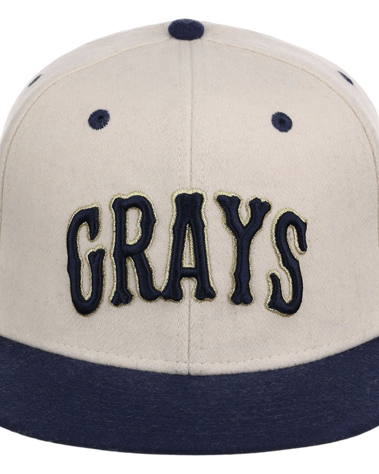 The Ebbets Field Homestead Grays NLB Ballpark Fitted Ballcap has a beige crown, dark blue brim, and GRAYS in bold dark blue letters on the front.