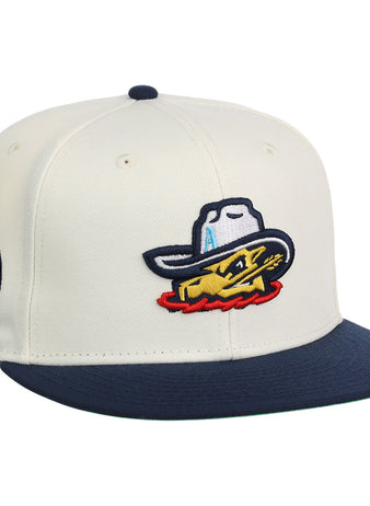 The Ebbets Field Amarillo Sod Poodles MiLB Snapback Ballcap is cream-colored with a navy brim, an embroidered yellow fish in a cowboy hat on the front, and a circular patch on the side.