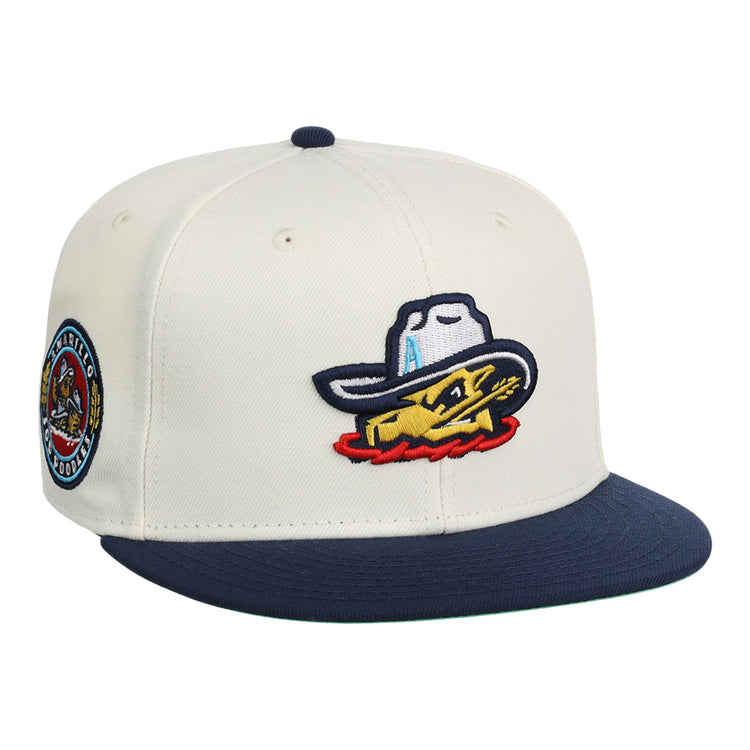 The Ebbets Field Amarillo Sod Poodles MiLB Snapback Ballcap is cream-colored with a navy brim, an embroidered yellow fish in a cowboy hat on the front, and a circular patch on the side.