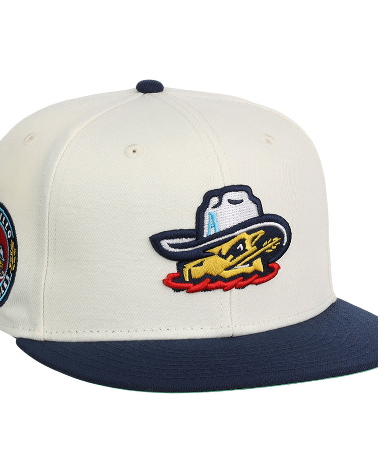 The Ebbets Field Amarillo Sod Poodles MiLB Snapback Ballcap is cream-colored with a navy brim, an embroidered yellow fish in a cowboy hat on the front, and a circular patch on the side.