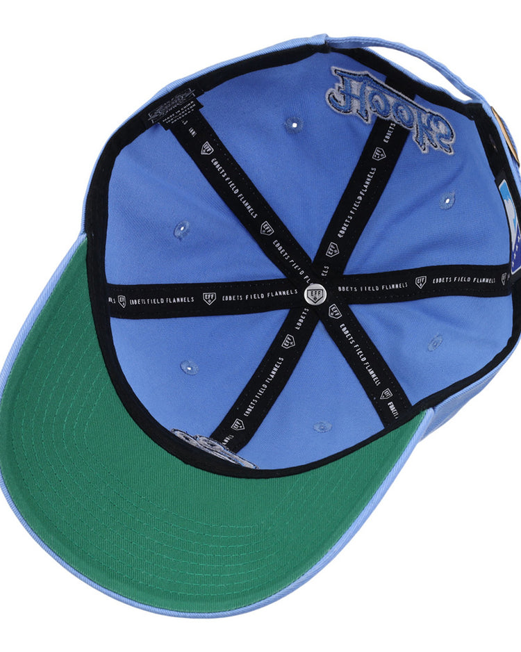 A light blue Ebbets Field Corpus Christi Hooks MiLB Dad Ballcap viewed from underneath, featuring a green underbrim, black CREW x FIELD FLANNELS interior taping, silver eyelets, and a Hooks logo embroidered inside.