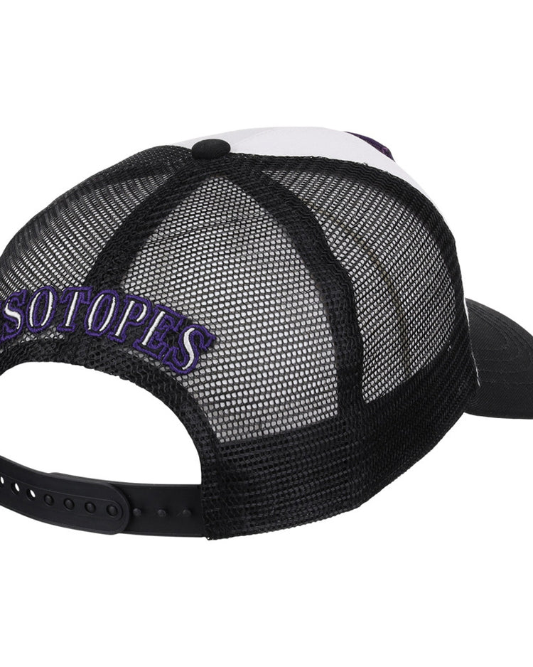 The Ebbets Field Albuquerque Isotopes MiLB Trucker Ballcap features black mesh, white front panels, and “ISOTOPES” embroidered in purple and white above the back opening.
