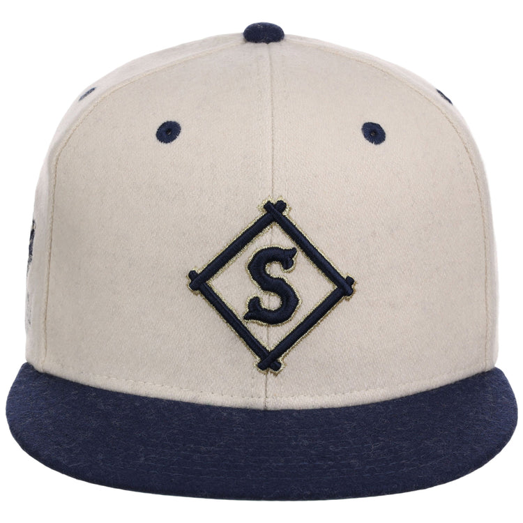 The Ebbets Field Seattle Steelheads NLB Ballpark Fitted Ballcap features a beige crown with navy blue brim and eyelets, plus a diamond-shaped S emblem embroidered on the front.