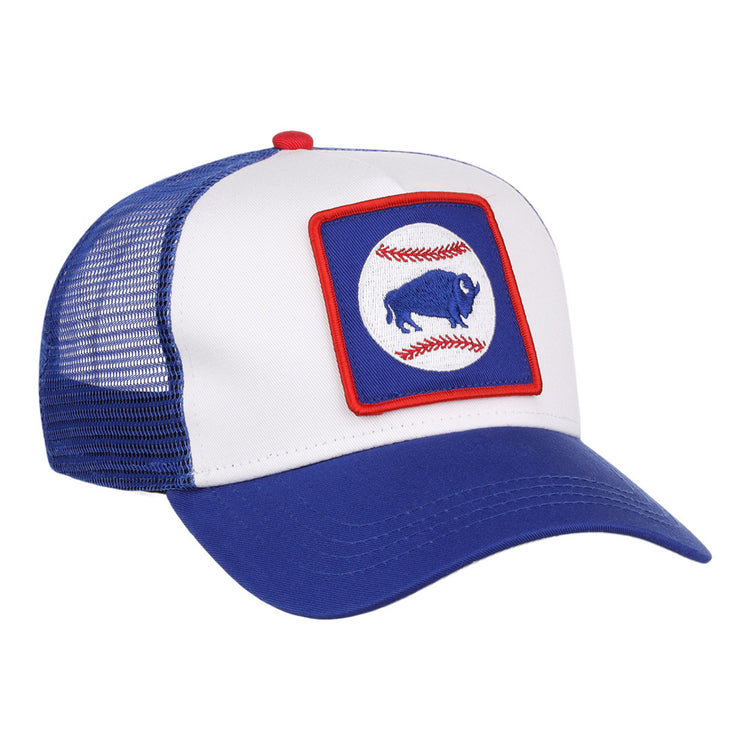 The Ebbets Field Buffalo Bisons MiLB Trucker Ballcap features a blue and white design with mesh back, plus a front patch showing a blue buffalo inside a red-bordered square, over two red baseball stitches on a white circle.