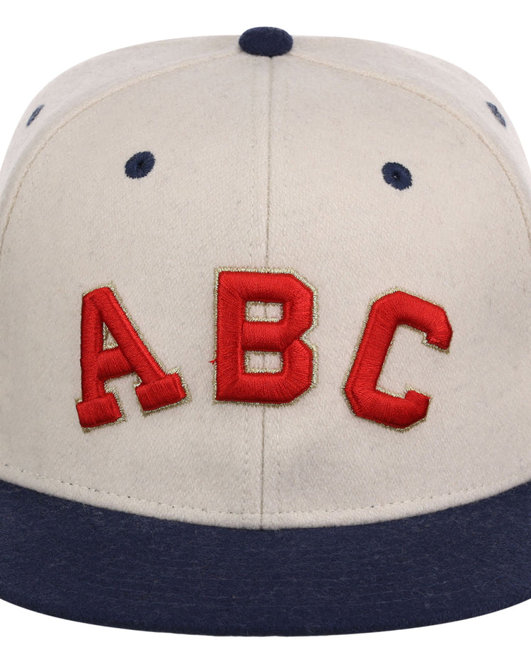 The Atlanta Black Crackers NLB Ballpark Fitted Ballcap by Ebbets Field is a beige cap with a dark blue brim, button, and eyelets, featuring large red 