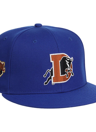 The Ebbets Field Durham Bulls MiLB Snapback Ballcap is a royal blue hat with an orange “D,” black bull logo on the front, and a commemorative patch on the left side.