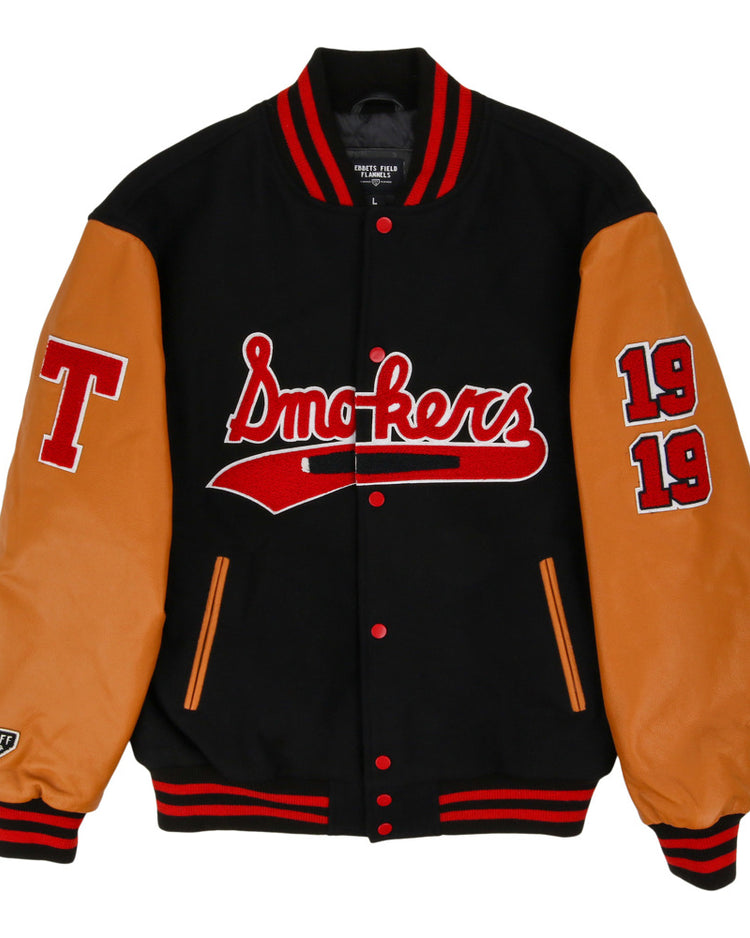 The Ebbets Field Tampa Smokers MiLB DNA Varsity Jacket features a black body, tan leather sleeves, red/white striped cuffs, 