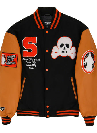 The Ebbets Field Sioux City Ghosts NLB Dna Varsity Jacket is black with orange sleeves and trim, adorned with a red S patch, white skull and crossbones, 