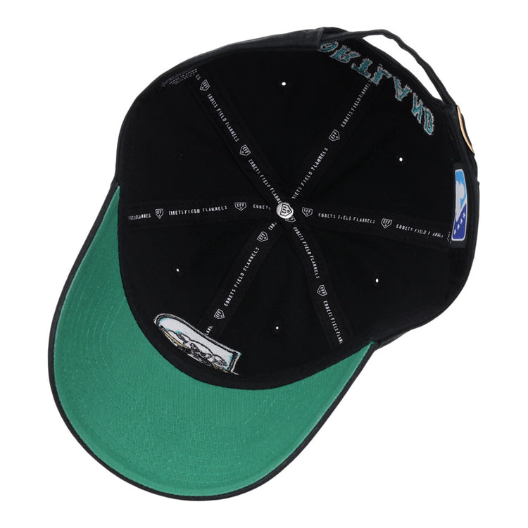 The Ebbets Field Portland Sea Dogs MiLB Dad Ballcap is shown from underneath, revealing its green underbrim, multiple printed labels inside, white text details, and a small graphic design.