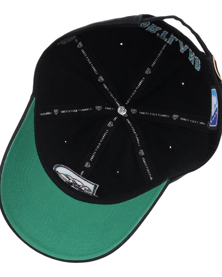 The Ebbets Field Portland Sea Dogs MiLB Dad Ballcap is shown from underneath, revealing its green underbrim, multiple printed labels inside, white text details, and a small graphic design.