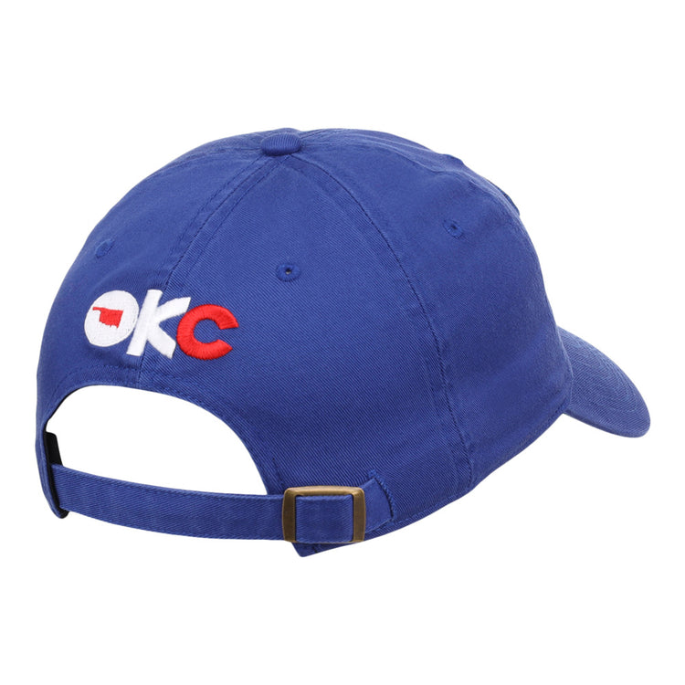 The Ebbets Field Oklahoma City Dodgers MiLB Dad Ballcap is blue, features OKC embroidered on the back in white and red with an Oklahoma outline in the O, and has an adjustable brass-buckle strap.