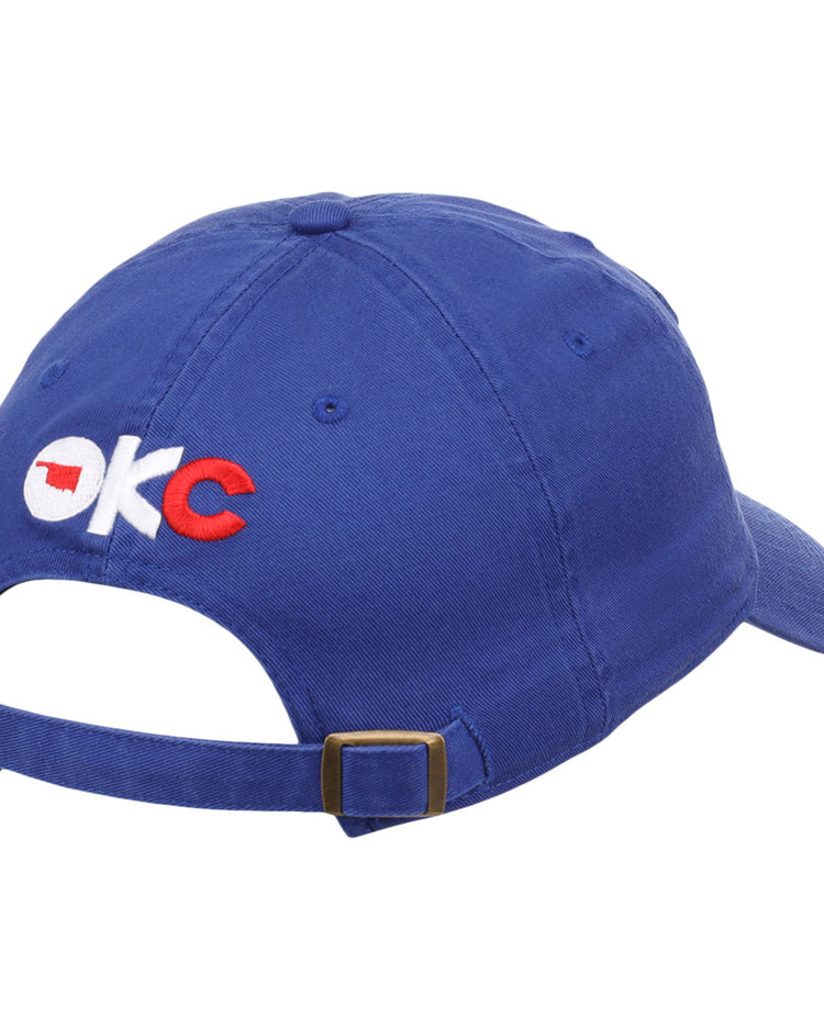 The Ebbets Field Oklahoma City Dodgers MiLB Dad Ballcap is blue, features OKC embroidered on the back in white and red with an Oklahoma outline in the O, and has an adjustable brass-buckle strap.