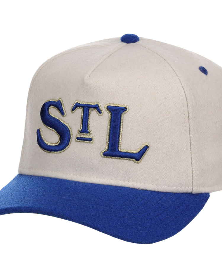 The Ebbets Field St. Louis Stars NLB Ballpark A-Frame Ballcap is beige with a royal blue brim and top button, featuring “STL” embroidered in blue and gold on the front.