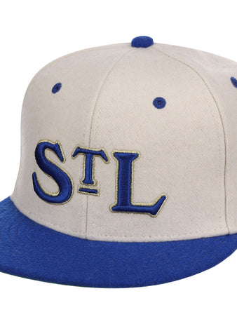 The Ebbets Field St. Louis Stars NLB Ballpark Fitted Ballcap features a beige crown, blue brim and button, and large blue “STL” letters with gold outlines embroidered on the front.