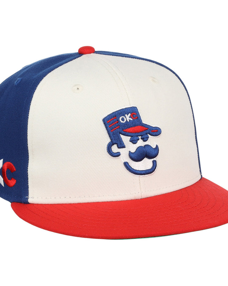 The Ebbets Field Oklahoma City 89Ers MiLB Snapback Ballcap features a white front, blue back, red brim, and a cartoon face with a blue cap embroidered with 