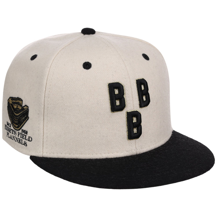 The Ebbets Field Birmingham Black Barons NLB Ballpark Fitted Ballcap is a white and black cap featuring three black “B” letters on the front and a side patch reading “1926 Bushs Field Planets” with a helmet design.