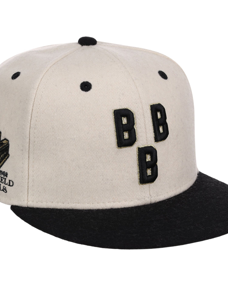 The Ebbets Field Birmingham Black Barons NLB Ballpark Fitted Ballcap is a white and black cap featuring three black “B” letters on the front and a side patch reading “1926 Bushs Field Planets” with a helmet design.