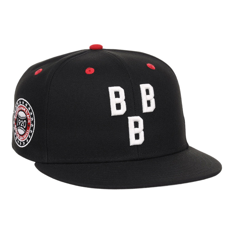 The Birmingham Black Barons NLB Varsity Fitted Ballcap by Ebbets Field is a black cap with three white embroidered Bs on the front, red accents on the top and vents, plus a circular patch with text and stars on the left side.