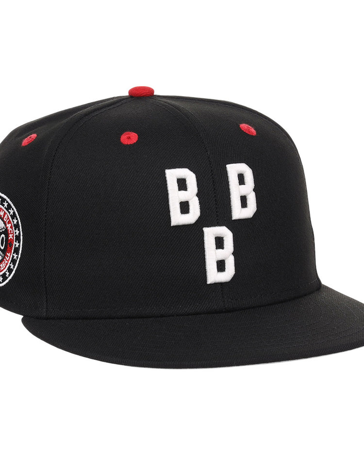 The Birmingham Black Barons NLB Varsity Fitted Ballcap by Ebbets Field is a black cap with three white embroidered Bs on the front, red accents on the top and vents, plus a circular patch with text and stars on the left side.