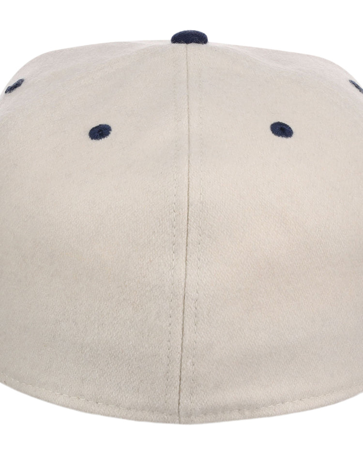 The Ebbets Field Homestead Grays NLB Ballpark Fitted Ballcap is beige, shown from the back with six navy blue eyelets and a matching navy button on top.