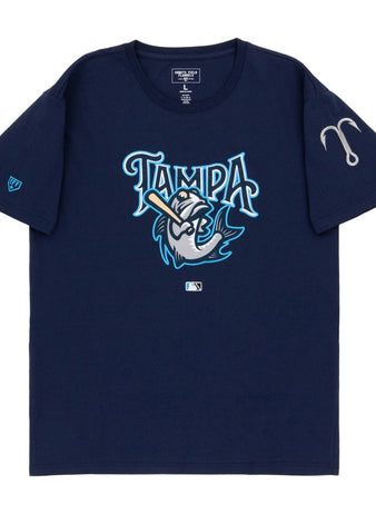 The Ebbets Field Tampa Tarpoons MiLB Fashion Cotton Short Sleeve Tee is a navy blue shirt with a stylized fish swinging a bat under the word “Tampa,” an MLB logo below, and a gray fishing hook on the left sleeve.