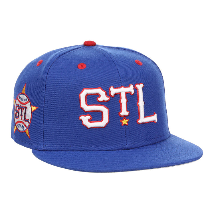 The Ebbets Field St. Louis Stars NLB Varsity Fitted Ballcap features a royal blue design, “STL” in bold white and red on the front, a side “St. Louis” patch, red accents, and a flat brim.