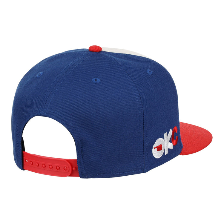 The Oklahoma City 89Ers MiLB Snapback Ballcap by Ebbets Field features a blue and red design, OKC embroidery on the side, and a red adjustable strap at the back.