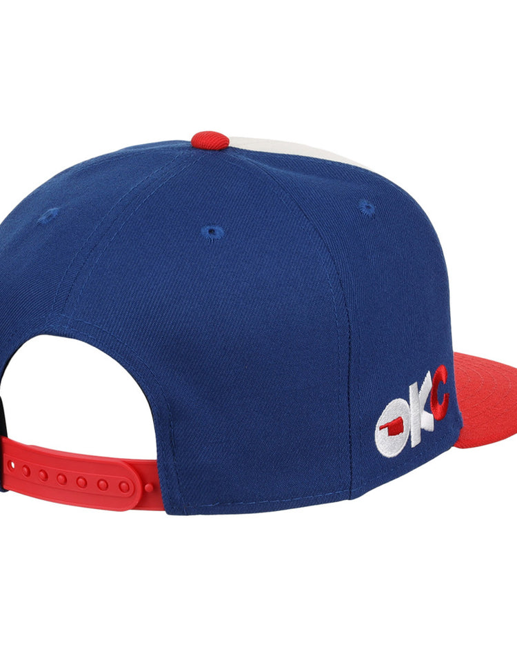 The Oklahoma City 89Ers MiLB Snapback Ballcap by Ebbets Field features a blue and red design, OKC embroidery on the side, and a red adjustable strap at the back.