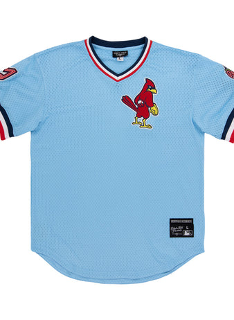 A light blue Ebbets Field Memphis Redbirds MiLB V-Neck Jersey with red, white, and navy trim, a cardinal logo on the chest, and patches on both sleeves.