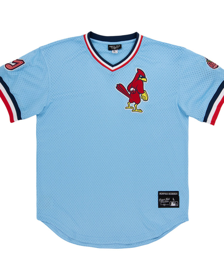 A light blue Ebbets Field Memphis Redbirds MiLB V-Neck Jersey with red, white, and navy trim, a cardinal logo on the chest, and patches on both sleeves.