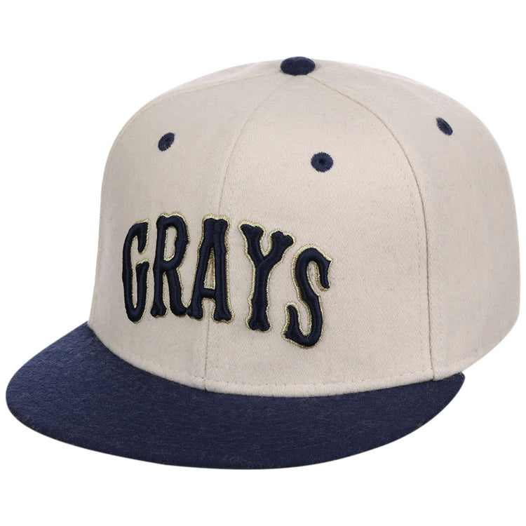 The Ebbets Field Homestead Grays NLB Ballpark Fitted Ballcap features a beige crown, dark blue brim, button, and eyelets, with 