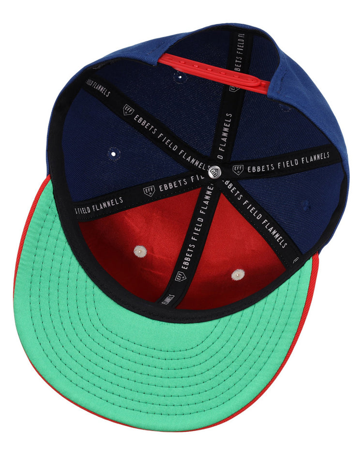 The Oklahoma City 89Ers MiLB Snapback Ballcap by Ebbets Field features a green underbrim, red brim edge, blue and red crown, and black interior bands labeled Ebbets Field.