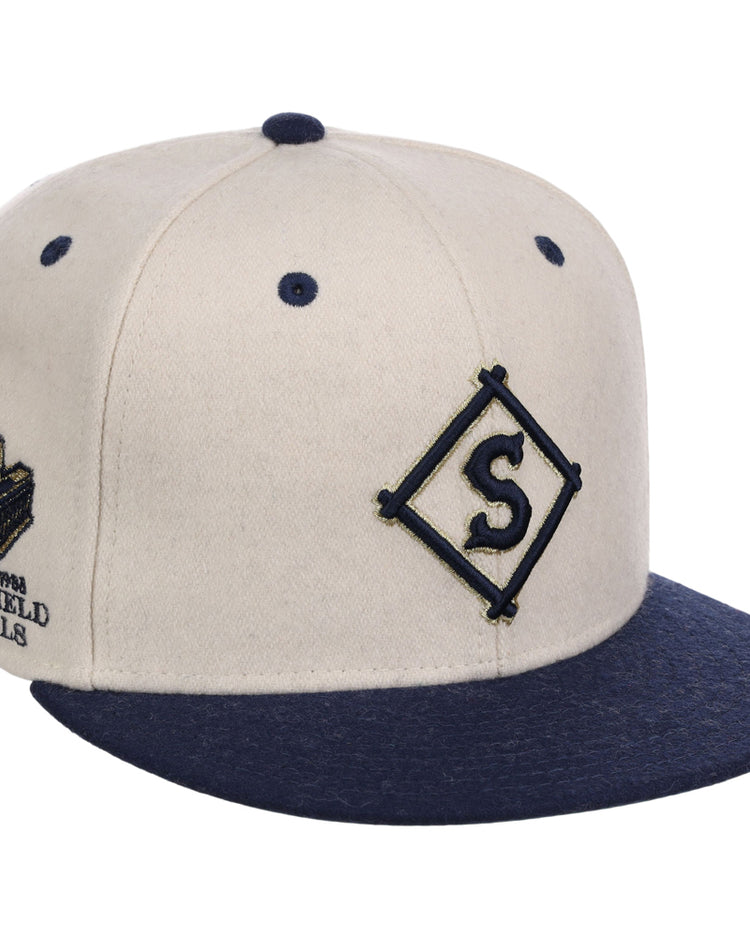 The Ebbets Field Seattle Steelheads NLB Ballpark Fitted Ballcap features a beige crown, navy brim, button, and eyelets. A navy diamond 