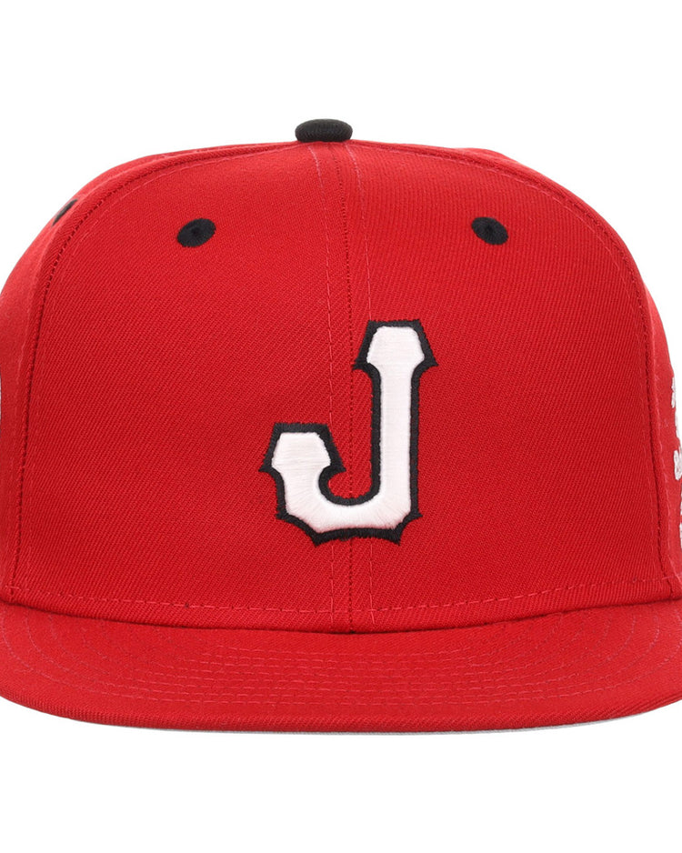 The Ebbets Field Jacksonville Red Caps NLB Varsity Fitted Ballcap is red with a white J outlined in black on the front, flat brim, black ventilation holes on top, and side patches.