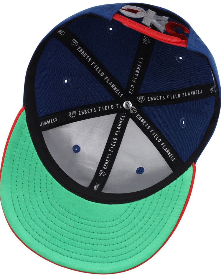 The underside of the Oklahoma City Dodgers MiLB Two Tone Snapback Ballcap by Ebbets Field features a green brim, black inner seams labeled EBBETS FIELD FLANNELS, blue inner panels, and a red edge around the brim.